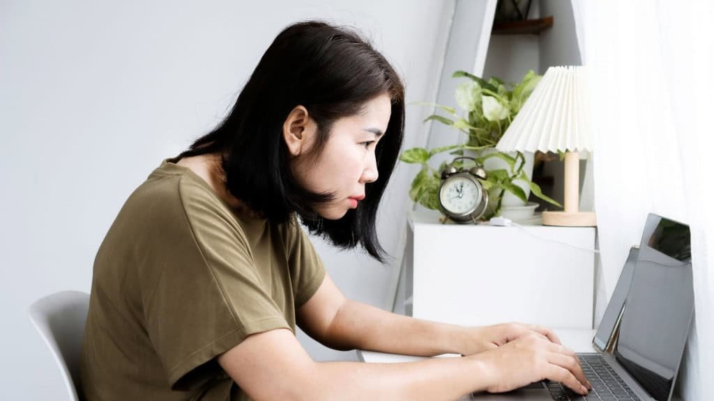 conceito de mulher asiática com cifose: visão lateral do laptop Trabalhar com as costas curvadas, postura da cabeça para frente e curvatura da coluna