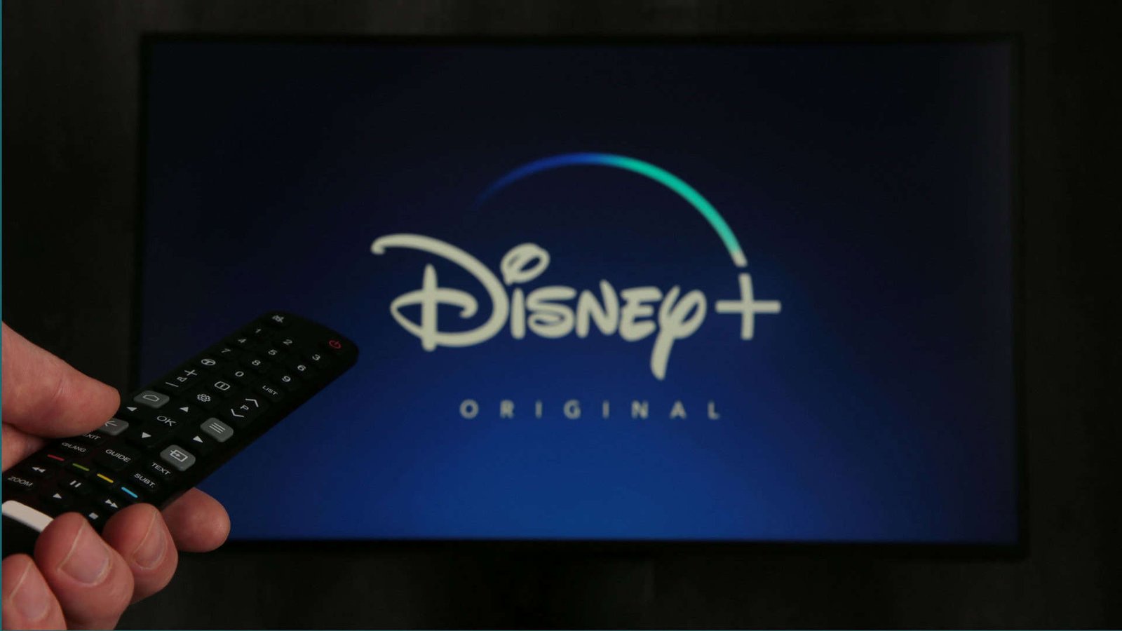 Tela de tv com o Disney+ aberto e uma pessoa com o controle remoto
