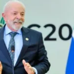 Presidente Lula sorri durante discurso oficial em púlpito; governo federal é criticado por manobras contábeis e aumento da dívida pública.