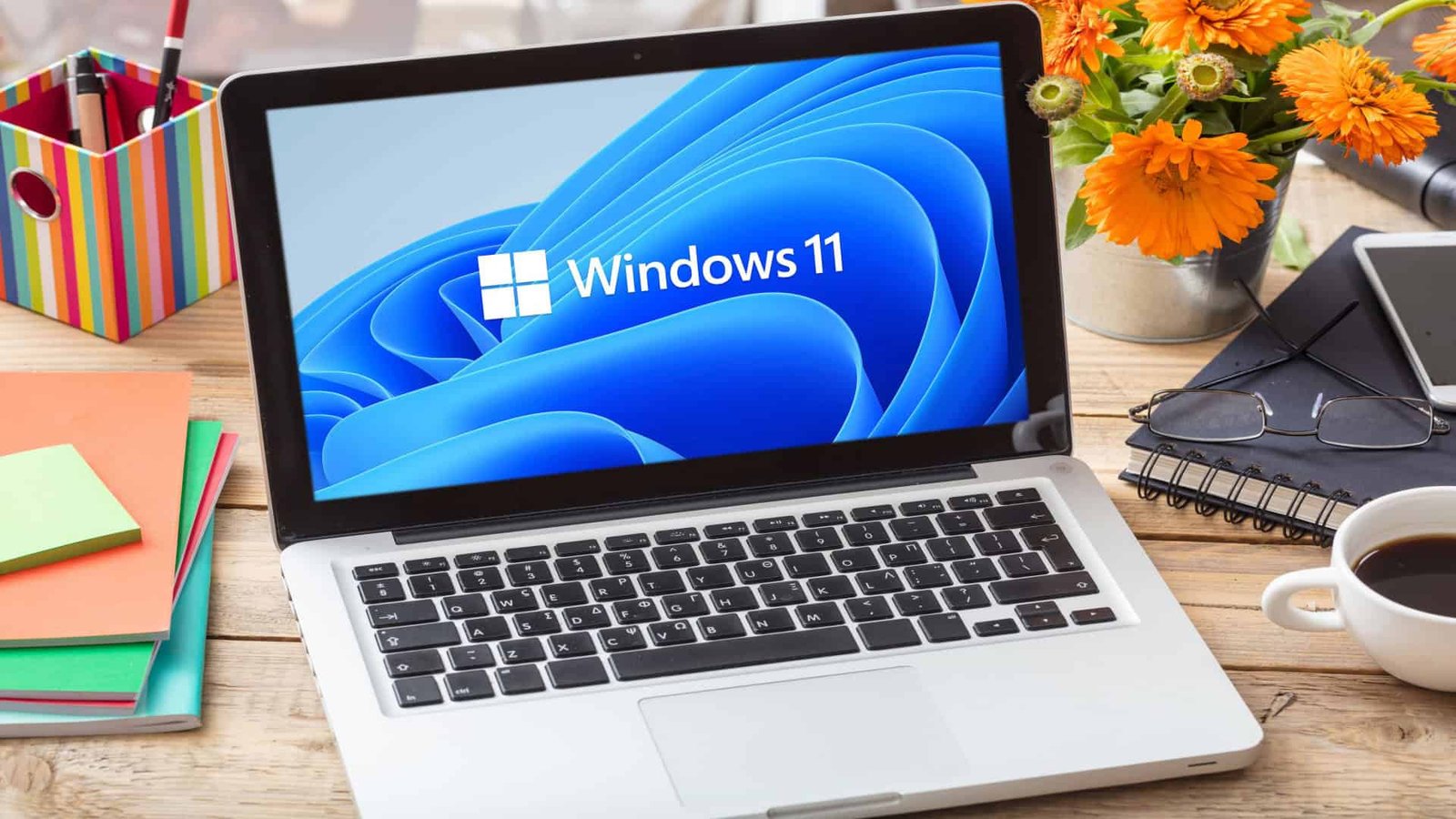 Imagem ilustrativa de logotipo oficial da marca Windows 11 na tela de um laptop em mesa de escritório