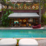 Fachada da Casa Conceito em São Paulo, com área externa integrada, piscina, paisagismo tropical e ambiente sofisticado iluminado.