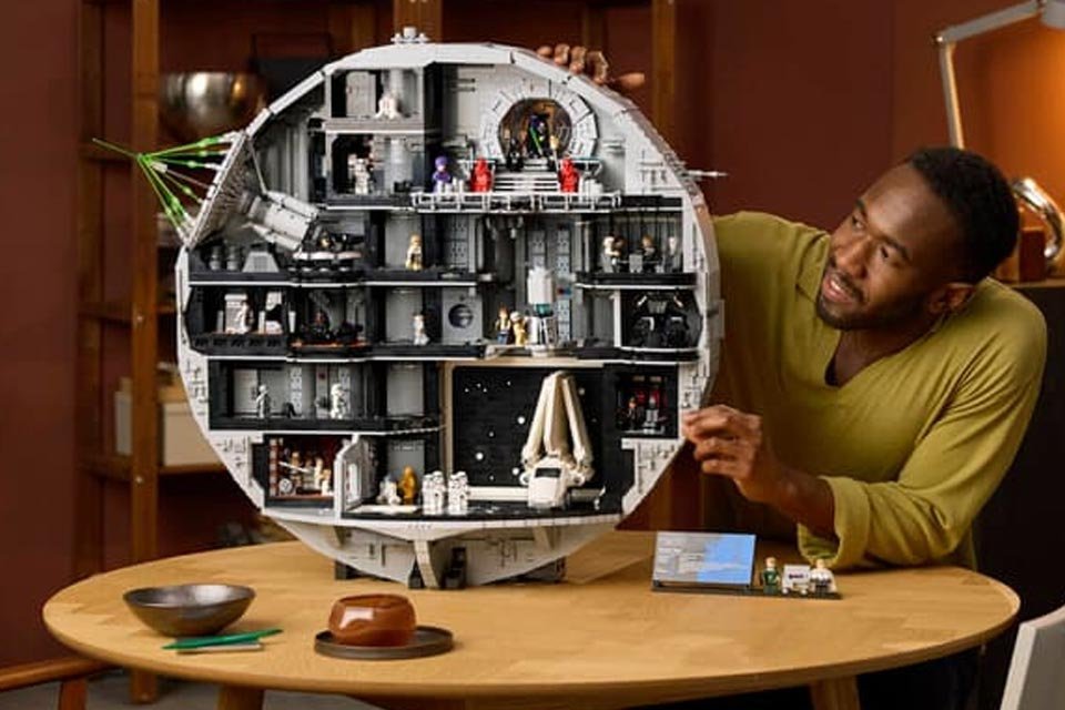 pessoa-ao-lado-do-conjunto-lego-star-wars-estrela-da-morte-montado-sobre-uma-mesa