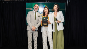 Mariléia Martins recebe reconhecimento durante participação na Confraria dos Palcos, ao lado de dois apresentadores em palco